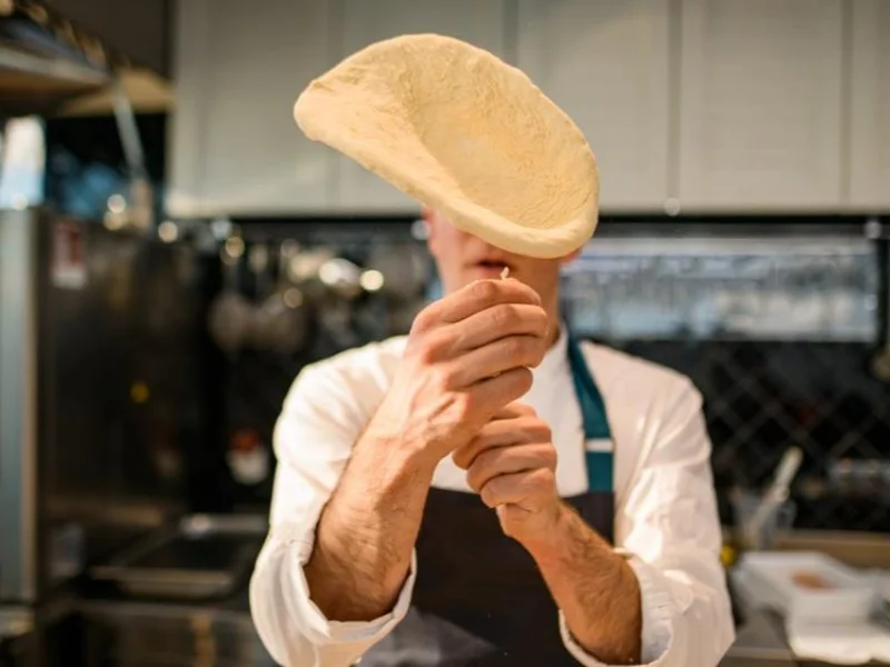 Fresh pizza dough being stretched by hand